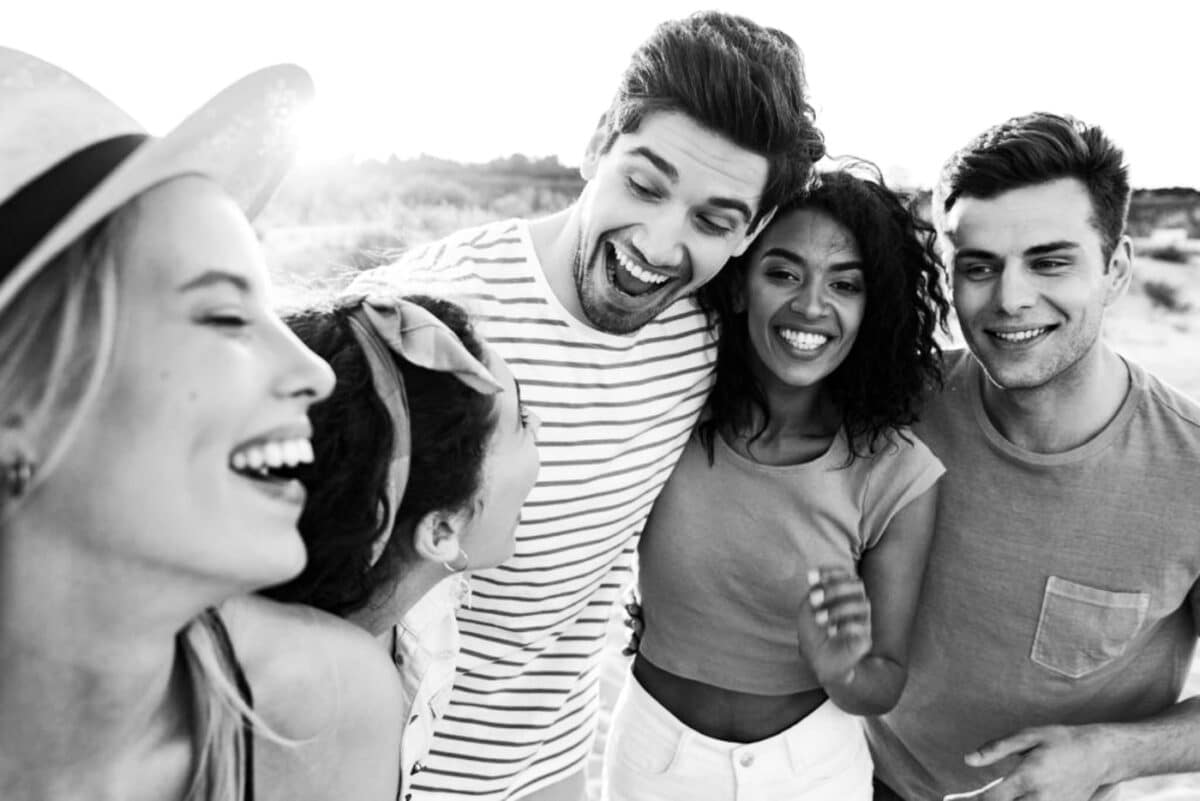 group of young adults hugging and laughing on the beach