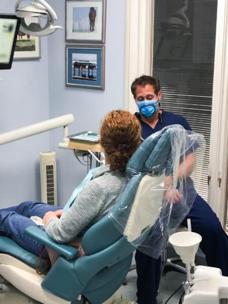 Patient in dentist chair speaking with dentist beach dental center