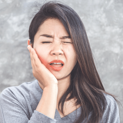 Woman holding her jaw in pain, representing dental problems