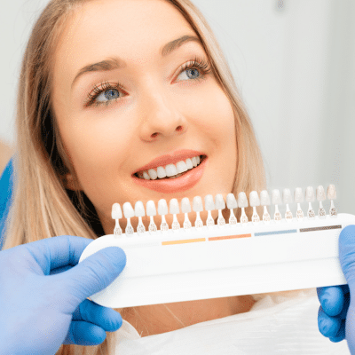 Woman at the dentist choosing color of teeth, representing cosmetic dental treatments