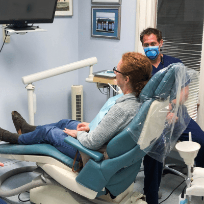 Dentist talking to a patient sitting in a dental chair, representing practical tips for dental anxiety
