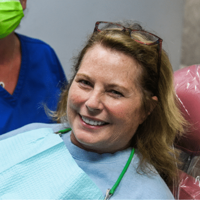 Woman smiling and sitting in a dental chair at beach dental center, representing how to maintain cosmetic dentistry results